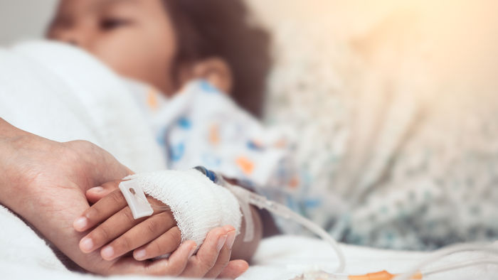 Mutter umfasst die Hand ihres Kind, das im Krankenhaus liegt